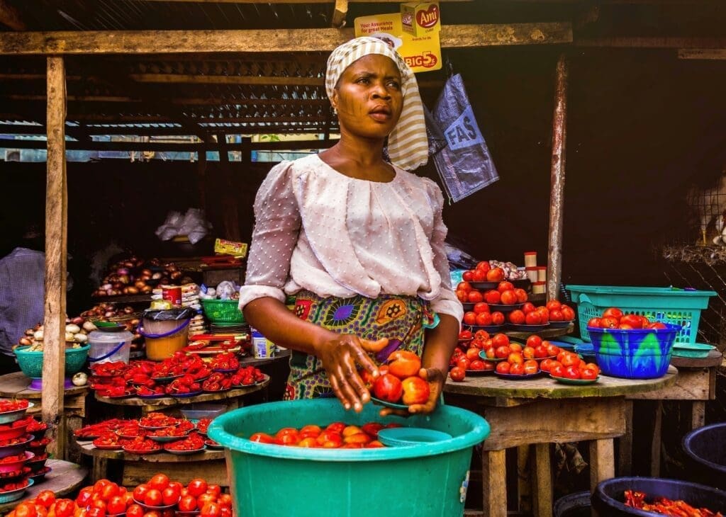 Local vendor in East Africa street market surrounded by produce