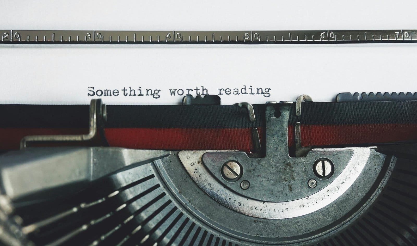 A close-up of a typewriter with the words "Something worth reading" typed on paper.
