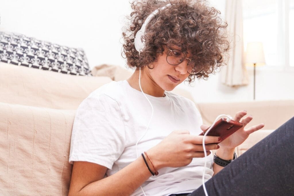 Person browsing mental health podcasts on a smartphone with headphones nearby