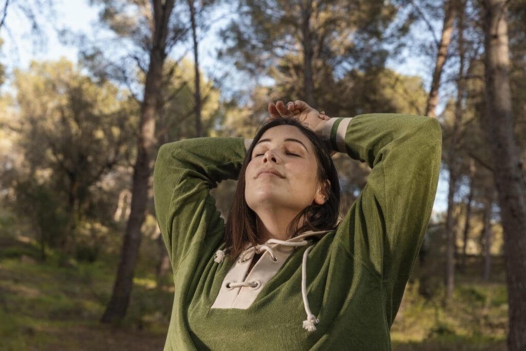 person standing still in a forest during forest bathing session for nature therapy
