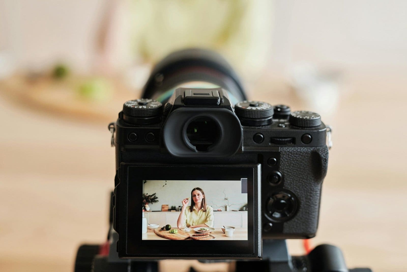 A DSLR camera with the screen showing a woman sitting at a table, recording or live streaming content, highlighting the creator economy.
