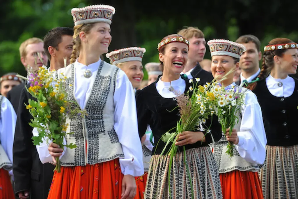Livonian people in traditional attire performing a folk dance near the Baltic Sea.