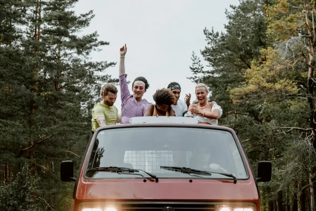 Group of friends enjoying a road trip in an open car, smiling and exploring hidden travel destinations together.