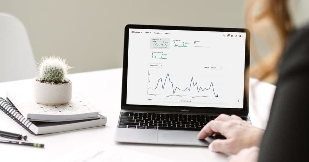 Travel blogger reviewing Pinterest analytics and engagement metrics on laptop.