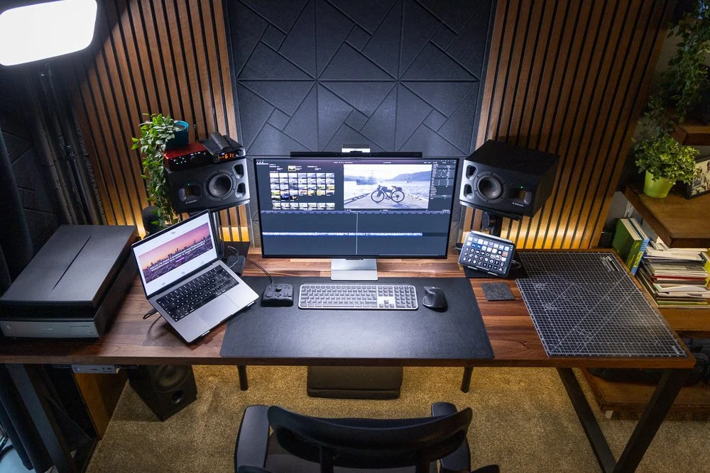 Creator editing photos on a laptop with a camera and neutral-toned props arranged on a minimalist desk.